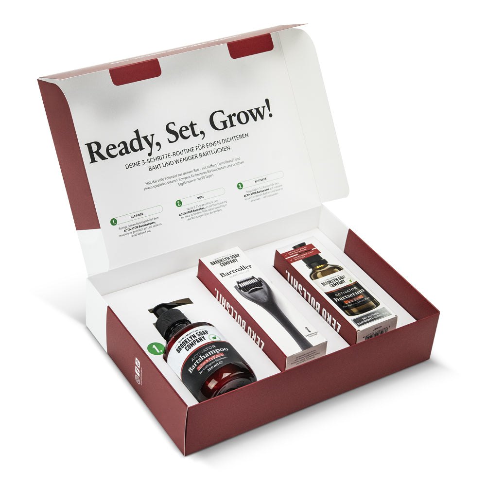 Bartpflege-Set mit drei Produkten in geöffneter Box: Shampoo, Derma-Roller und Aktivserum unter dem Slogan „Ready, Set, Grow!“.