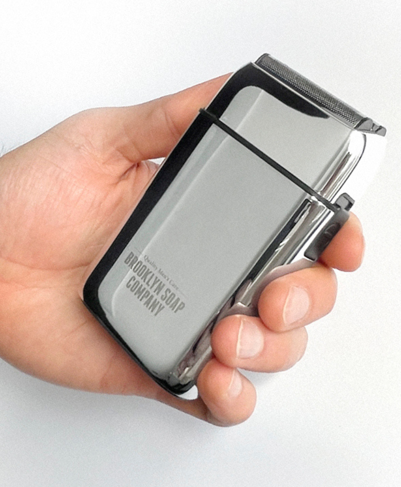 Detailaufnahme des Brooklyn Soap Company Shavers – elektrischer Rasierer mit präzisen Edelstahl-Scherköpfen auf Produktverpackung.