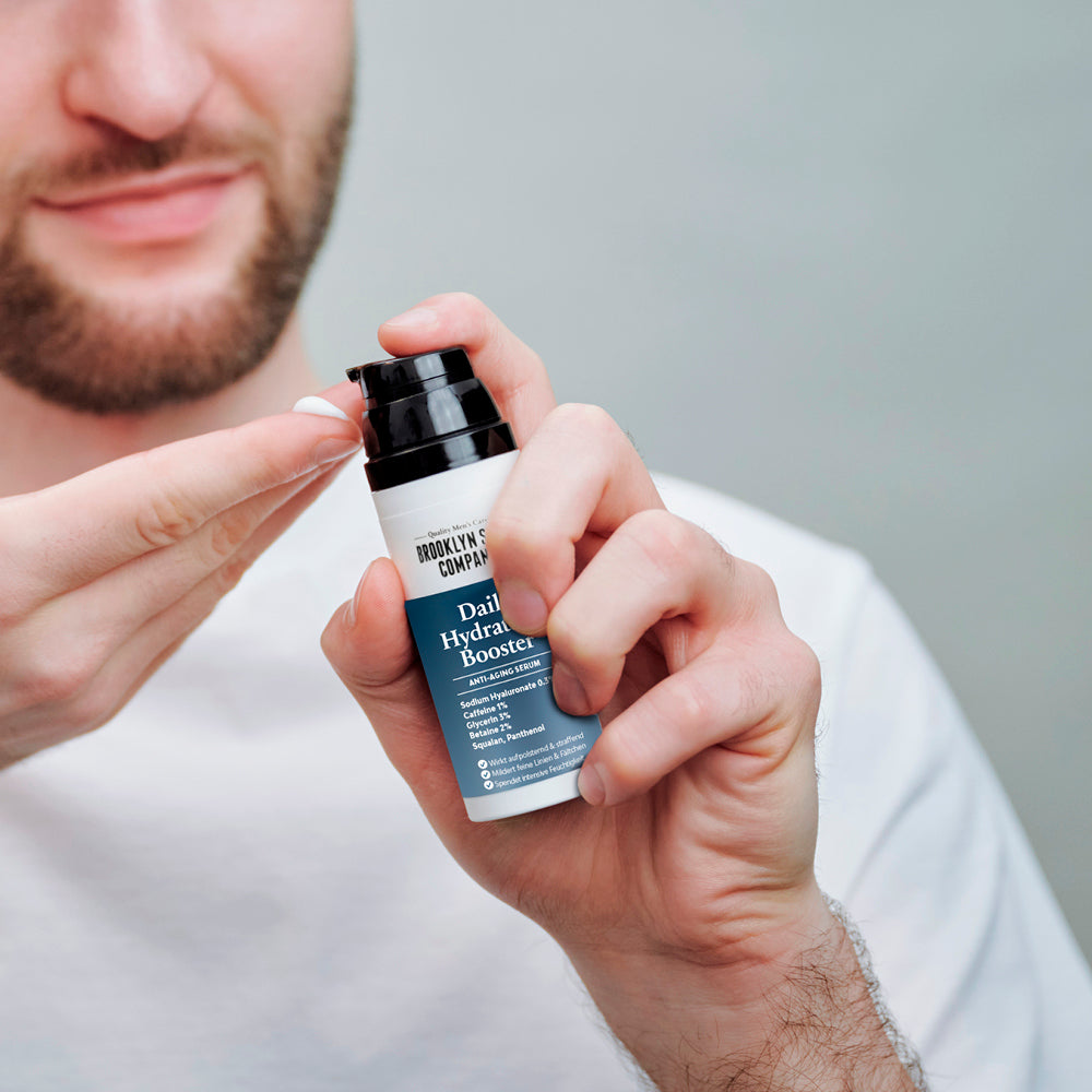 Mann trägt „Daily Hydration Booster“ von Brooklyn Soap auf; Text hebt Anti-Aging, Feuchtigkeit und Pflegeroutine hervor.