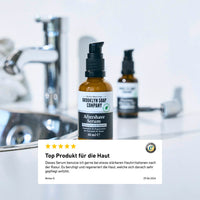 Flasche des Brooklyn Soap Company Aftershave Serums auf einem Waschbeckenrand, mit Kundenbewertung im Vordergrund über die hautberuhigende Wirkung des Produkts.