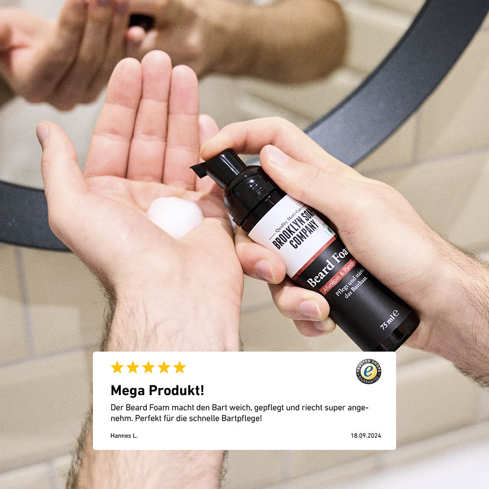 Der Bartschaum pflegt den Bart intensiv, spendet trockenen Barthaare Feuchtigkeit und gibt ihm Halt. Beard Foam wird auf die Hand aufgetragen, im Hintergrund Spiegelbild, darunter eine Kundenbewertung zur Wirkung.