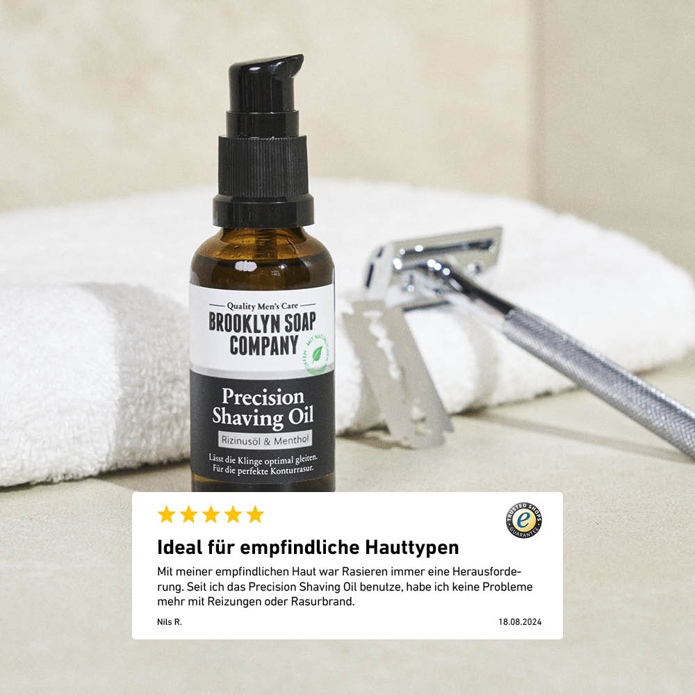 Precision Shaving Oil steht neben einem Rasierhobel und Handtuch im Bad, darunter Kundenbewertung zur Wirkung bei empfindlicher Haut.